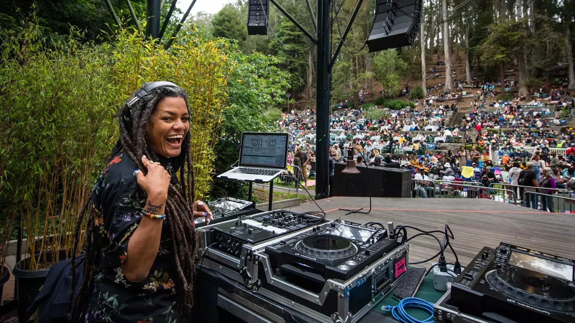 A woman DJing at the 斯特恩林 Festival looks over her shoulder and smiles into the camera.