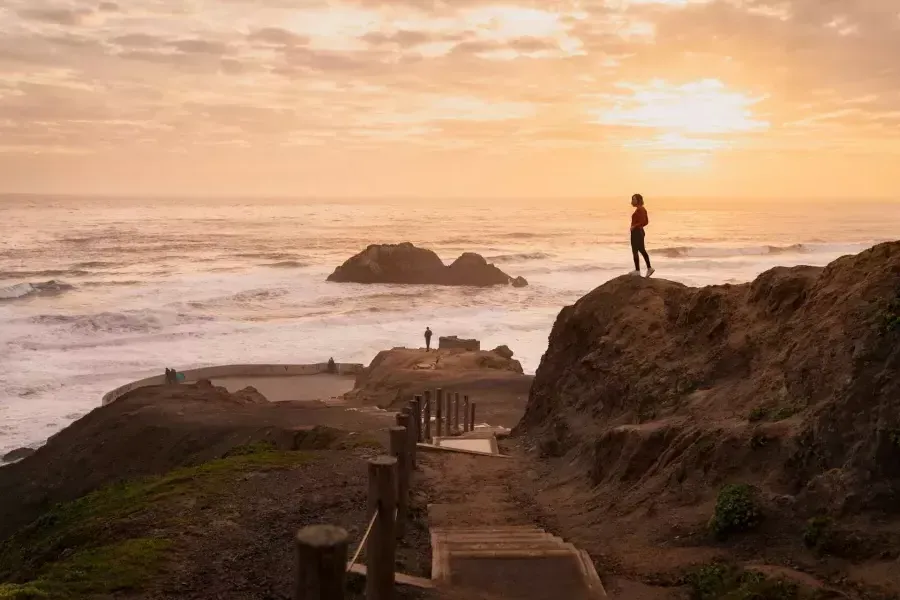 Deux personnes se tiennent debout sur des rochers surplombant l’océan aux Sutro Baths à 贝博体彩app.