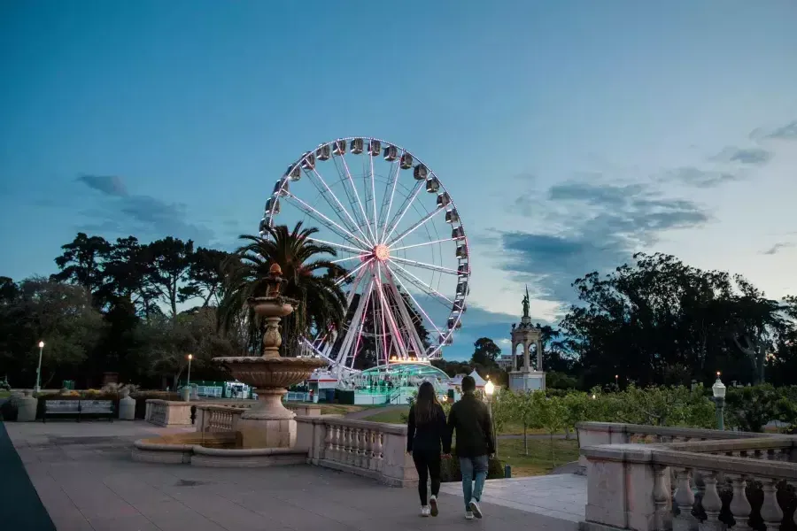 Un couple se dirige vers la grande roue SkyStar au crépuscule.