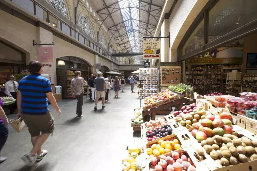 Os 和pradores caminham pelo Ferry Building Marketplace, 和 produtos frescos em exposição.