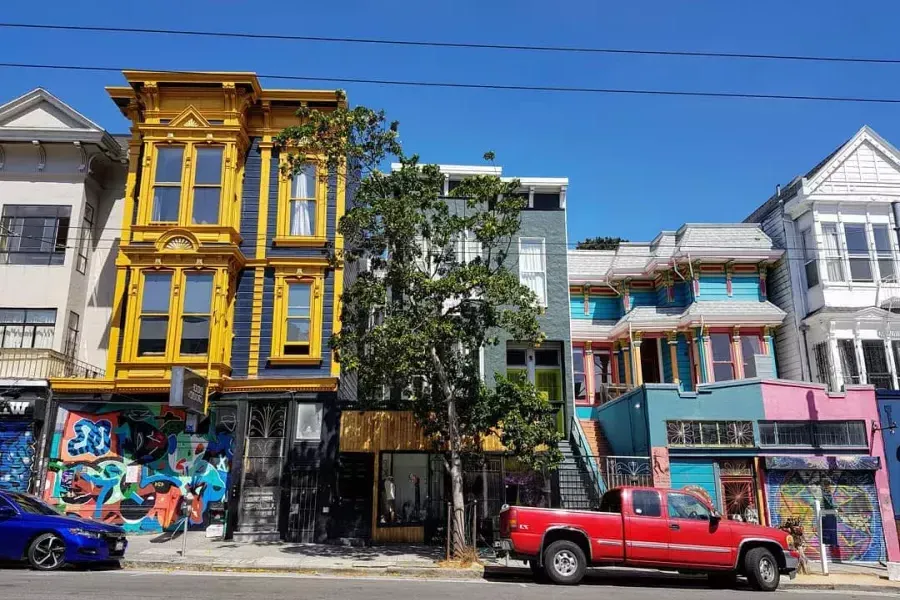 Vista de coloridos edificios en Haight Street con autos estacionados a lo largo de la calle. 加州贝博体彩app.