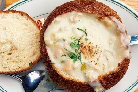 Sopa de mariscos servida em tigela de pão de massa fermentada