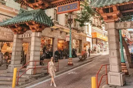 Una donna posa davanti a un cancello decorato che segna l'ingresso della Chinatown di San Francisco.