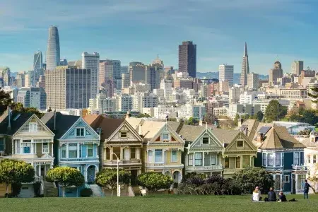 Picnickers sit on the grass at Alamo Square Park 与 the 涂女士 and San Francisco skyline in the background.