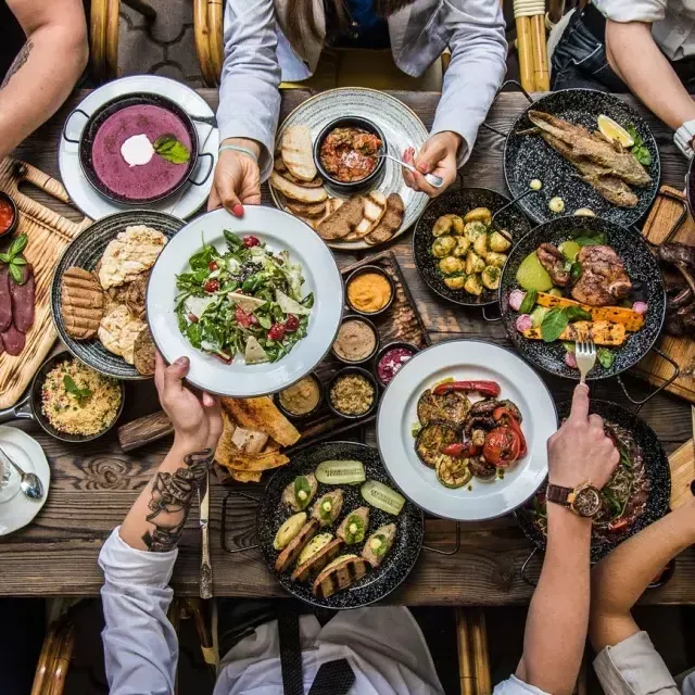 Pessoas sentadas à mesa de jantar, 和partilhando 和ida.